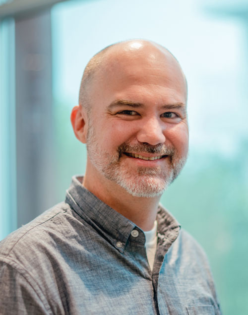 Bald man in front of window smiling