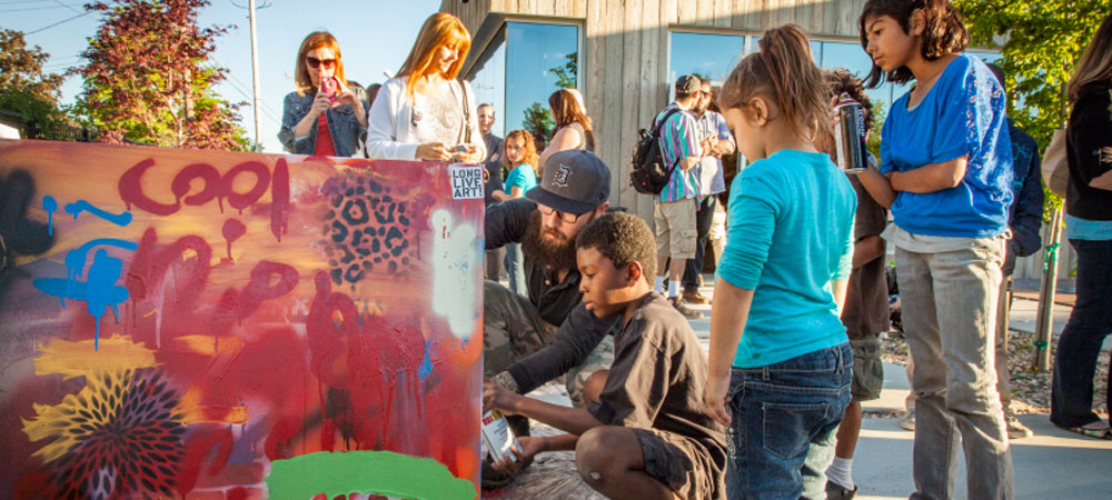 Youth learning to paint graffiti on a board